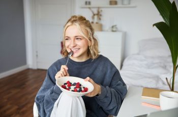 білява дівчина смакує зелений салат вдома