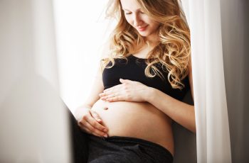 вагітна жінка радіє вагітності, дивиться посміхаючись